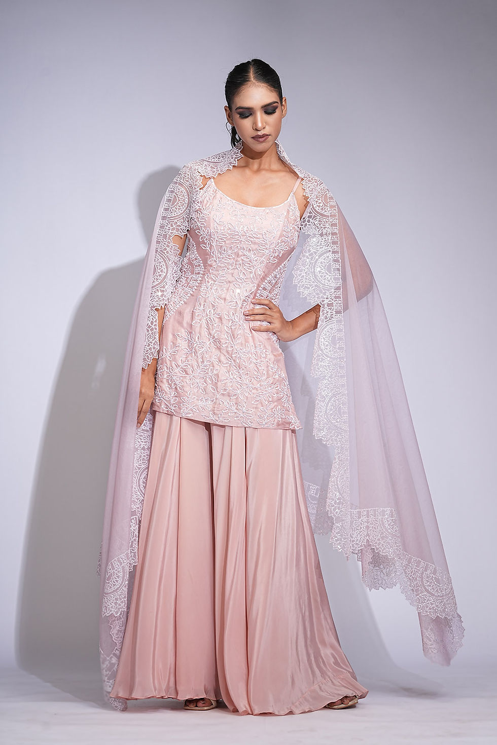 Model wearing powder pink sharara suit with embroidered silk kurta and scalloped organza dupatta by SHRUTI S,