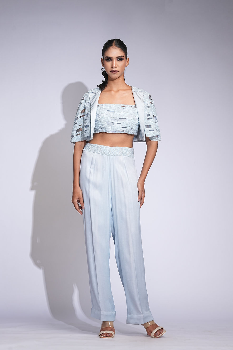 Thumbnail: Model wearing powder blue co-ord pant set with crop top and cape-style embroidered jacket by SHRUTI S – cocktail & event wear