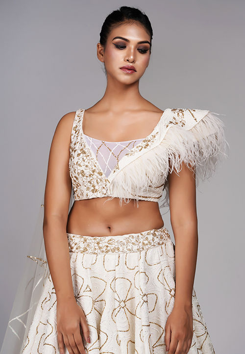 Thumbnail: Close-up of golden thread embroidery and feather trim on off-white blouse