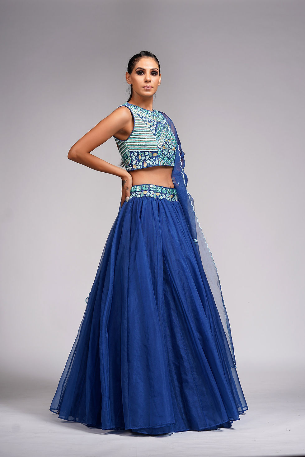 Thumbnail: Side view of royal blue lehenga featuring flowing organza fabric and matching detailed embroidery on the blouse and dupatta