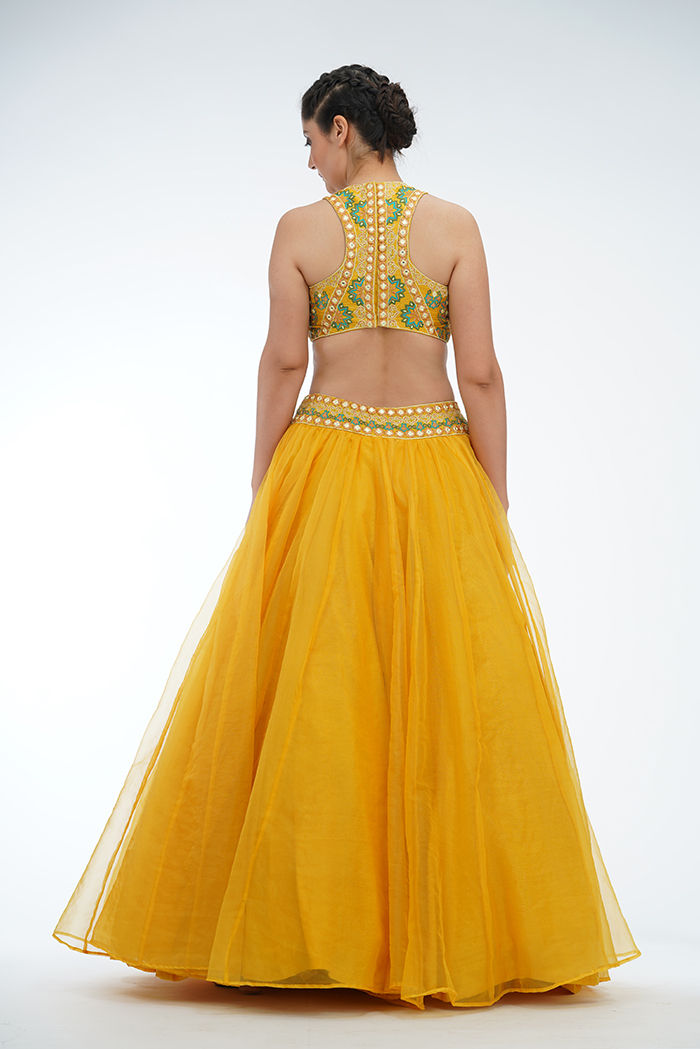 Back view of yellow lehenga choli with flowing organza silhouette and sheer tassel dupatta in motion