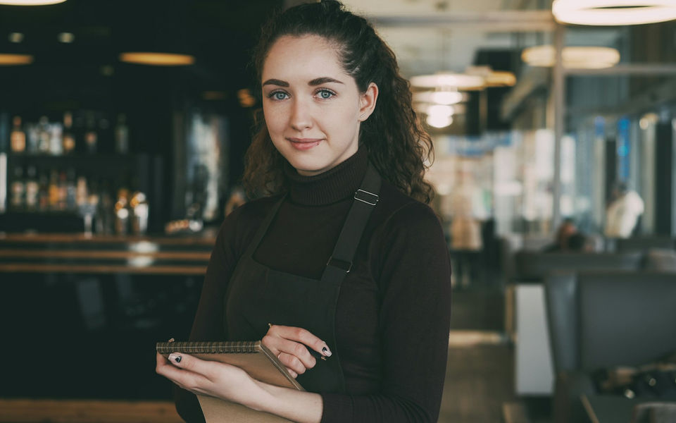 Server in an apron holding an order pad on the restaurant floor