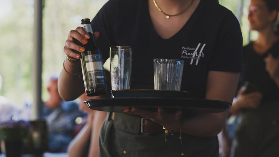 Server carrying a tray of glasses and a bottle in a restaurant