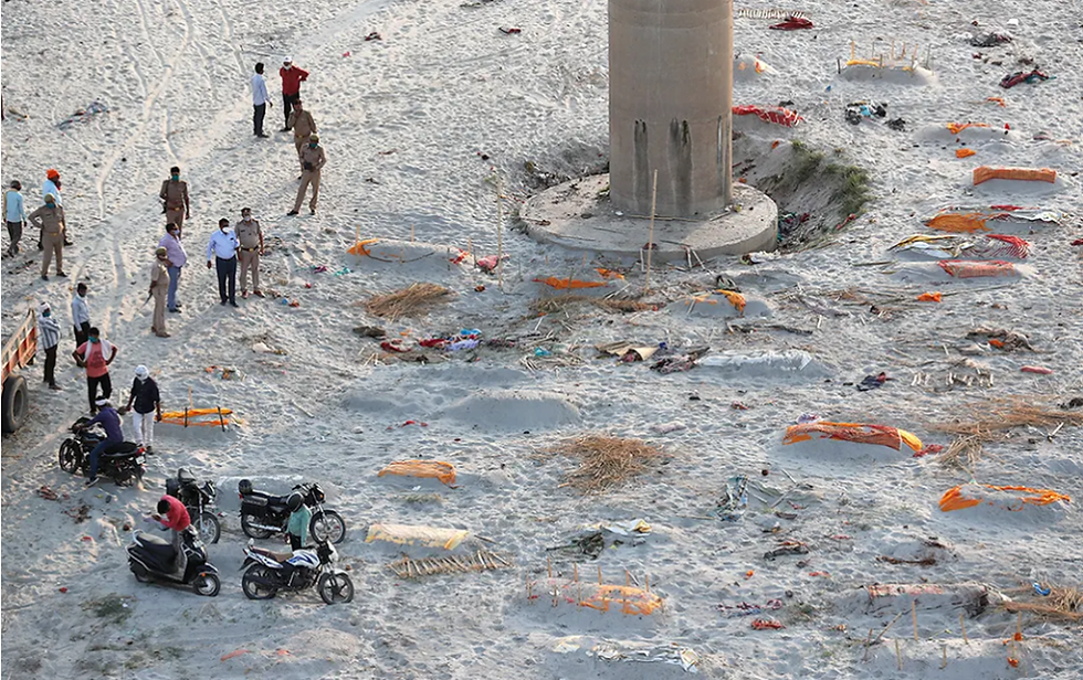 Source: Associated Press // Policemen stand next to shallow graves on the banks of the Ganges