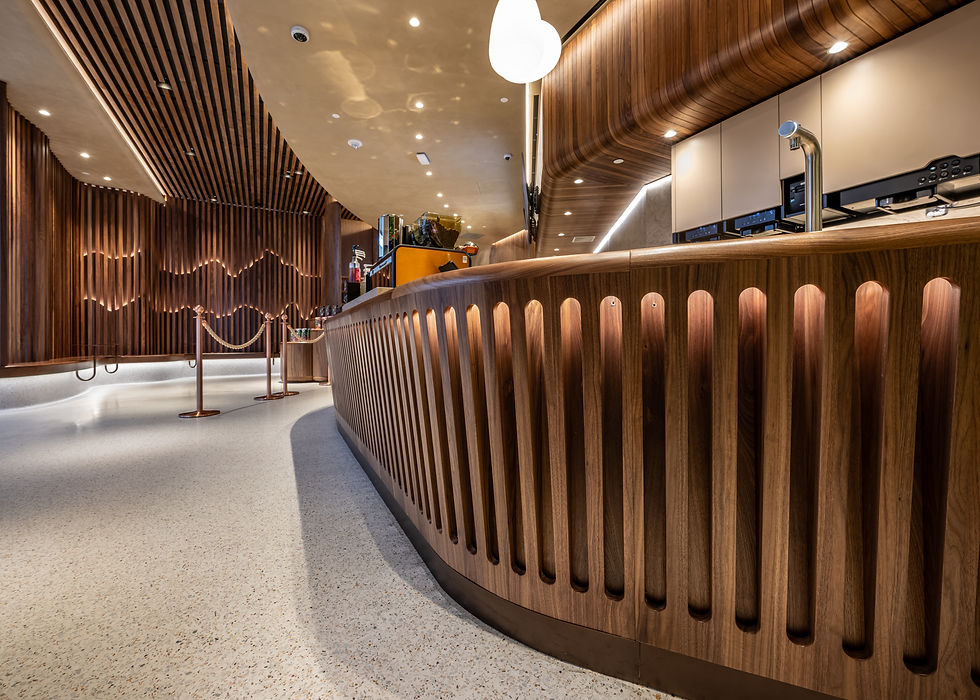 Contemporary coffee bar with curved wood paneling, recessed lighting, and custom millwork showcasing craftsmanship.