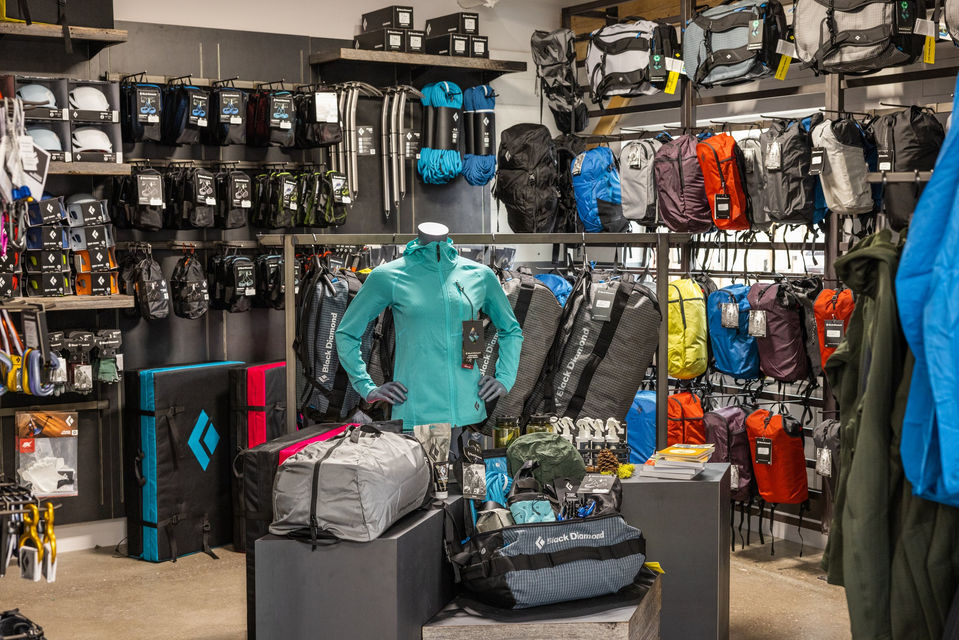 Section of the store featuring mannequins, performance apparel racks, and a wall filled with climbing gear including ropes, helmets, and accessories.