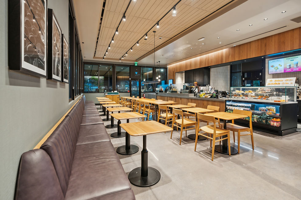 Wide-angle view of a coffee shop interior with seating, service counter, and lighting emphasizing clean modern design.