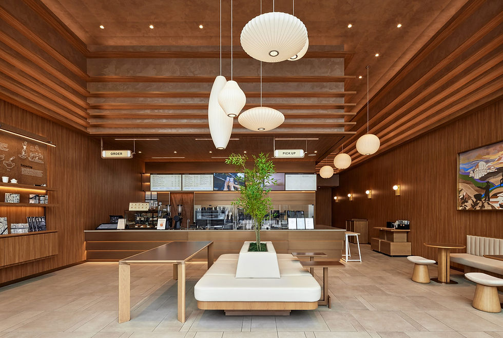A high-end coffee shop featuring warm wood paneled walls, beautiful lighting fixtures and gold tables.