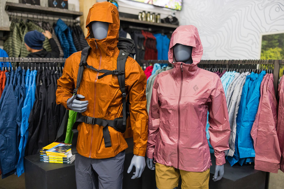 Male and female mannequins wearing Black Diamond technical jackets and outdoor clothing, surrounded by color-coordinated outerwear on retail racks.