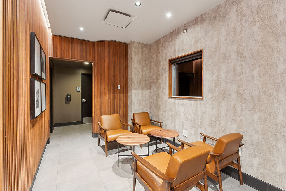 Small seating area in a coffee shop with mid-century style chairs, wood finishes, and accent lighting.