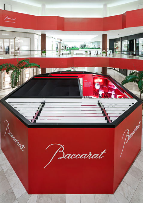Baccarat kiosk in mall setting with red branding and luxury fragrance retail design.