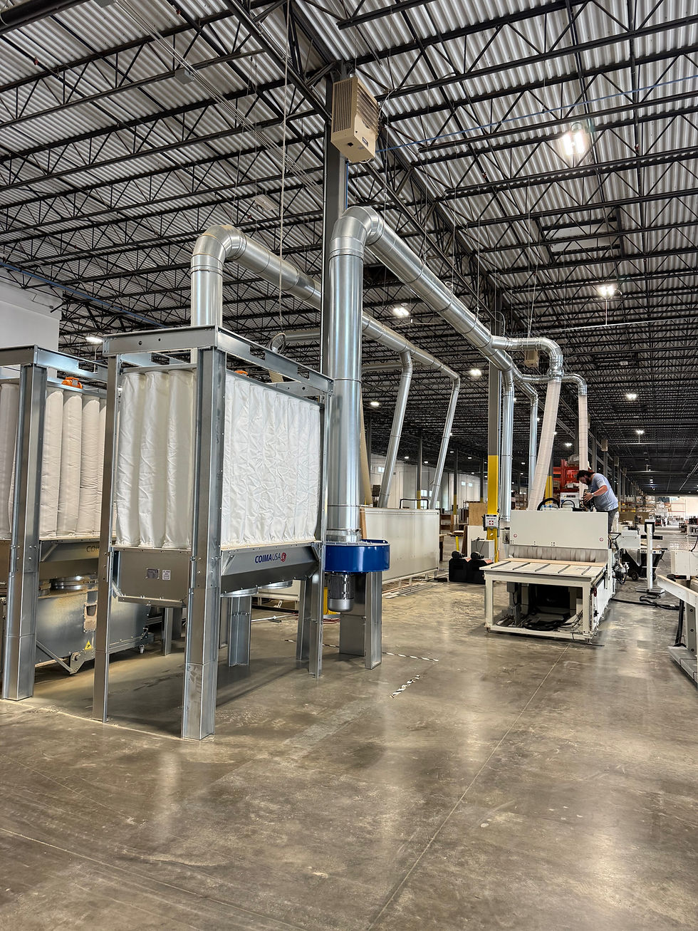 A man works at a CNC machine in a large warehouse.
