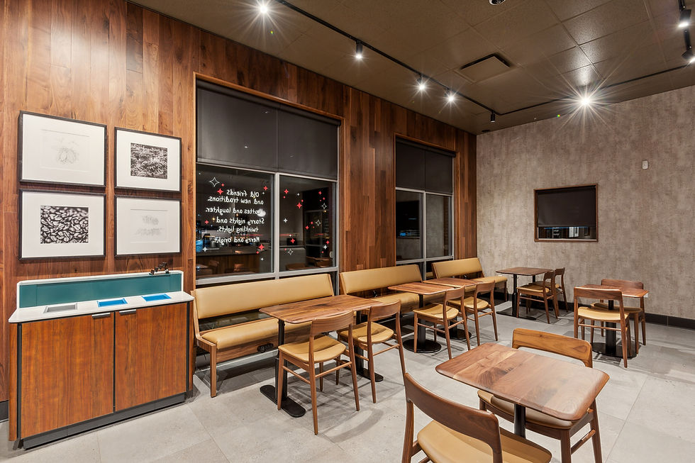 Coffee shop seating area with wood paneling, framed artwork, soft lighting, and a welcoming modern design.