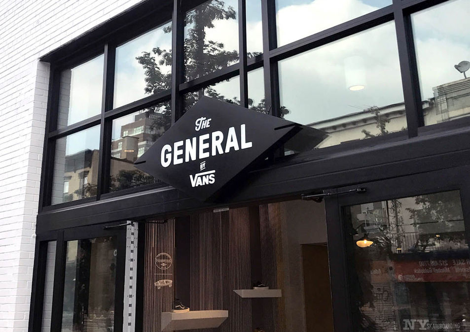 Exterior view of The General by Vans store in Brooklyn, featuring large glass doors and illuminated signage leading into a modern retail space with custom shoe displays.