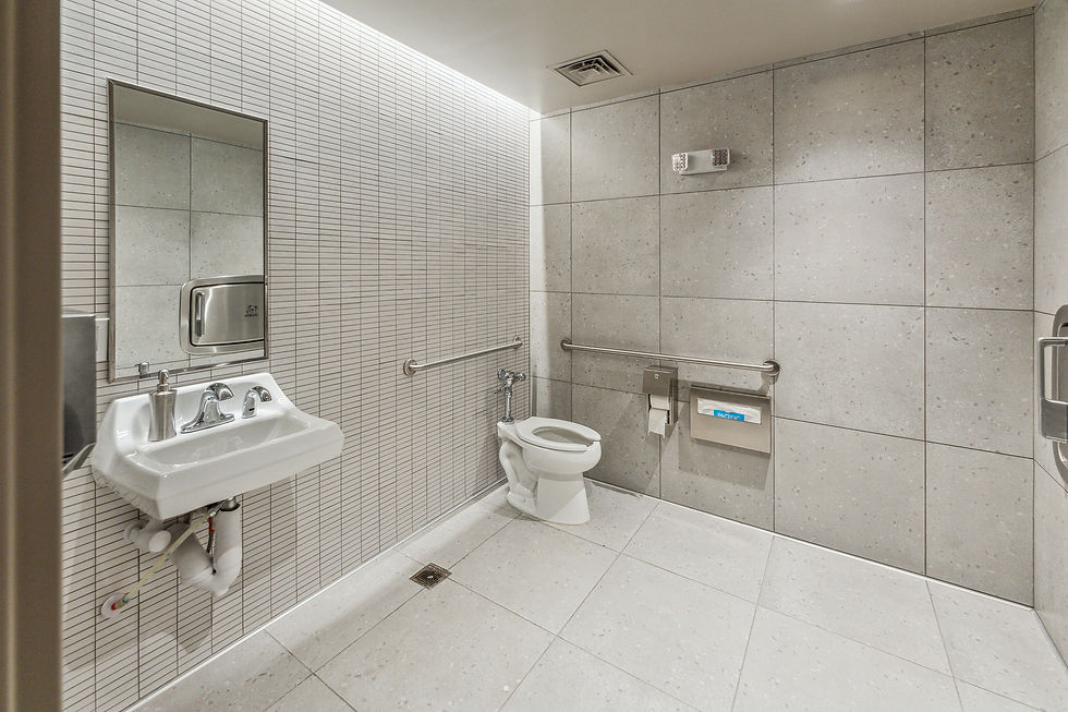 Modern restroom with tiled walls, accessible fixtures, and minimalist design for commercial coffee shop interior.