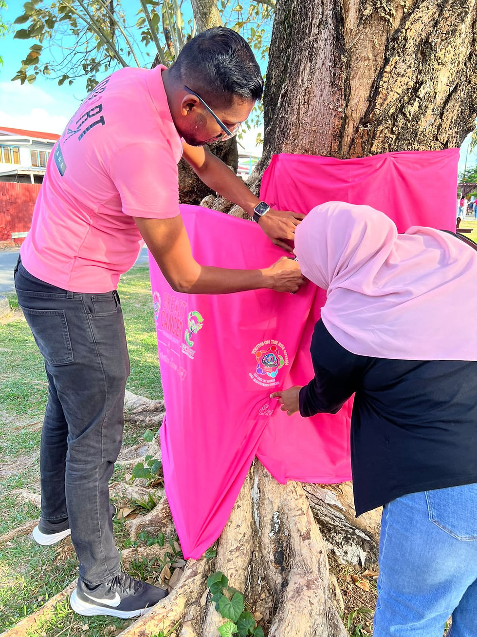 Recover Guyana team members, Mr. Vishal Roopnarine and Ms. Alieyah Gaindalall, participate in tree wrapping as part of the Pink Steps Sunday initiative.