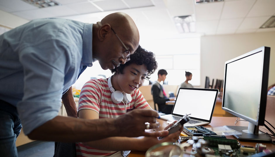 African-American male instructor assisting young Asian-American student with an assistive technology device