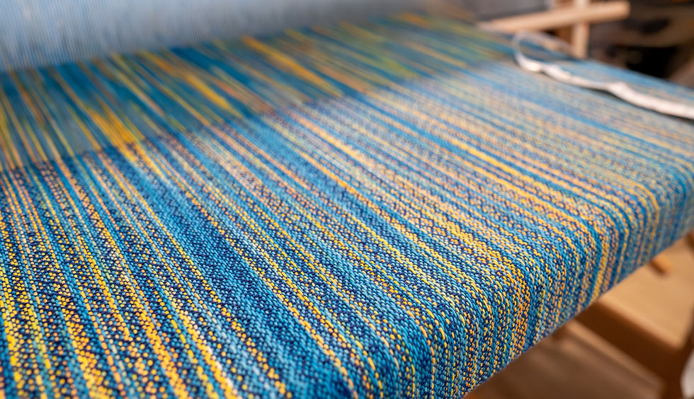 Hand dyed fabric being woven on a floor loom
