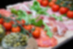 Colorful antipasto platter featuring cherry tomatoes, prosciutto, capers, and sliced cured meats, arranged by Chalk & Cheese