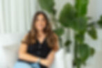 Social media manager Hannah smiling on a sofa with indoor plants, representing Grid Socials’ friendly brand tone