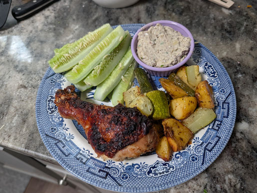 A finished plate of Greek chicken with sides and yam berry hummus.