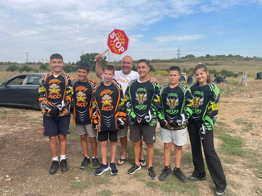 Група деца с пейнтбол фланелки и табела СТОП на открито. ЯкоЕ