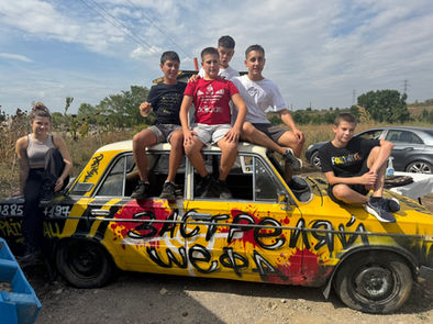 Група тийнейджъри на жълта кола със Застреляй Шефа надпис. ЯкоЕ.