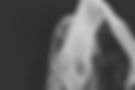 Black and white portrait of a figure draped in translucent fabric against a dark background