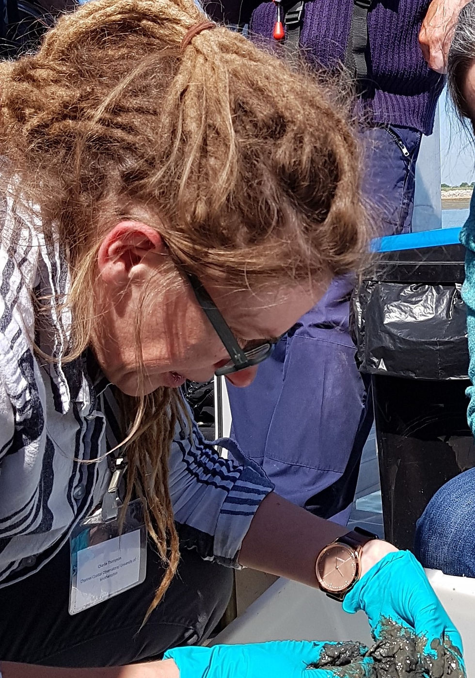 Image of Charlie conducting a sediment grab, looking at materials in white tray