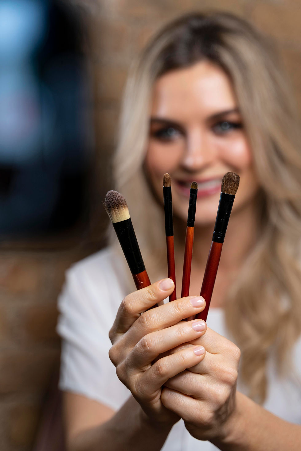 Woman holding four makeup brushes