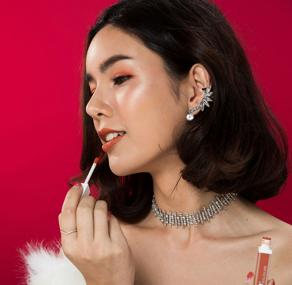 Woman applying lip gloss, red background