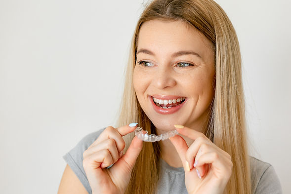 Beautiful cheerful woman is holding an invisalign bracer