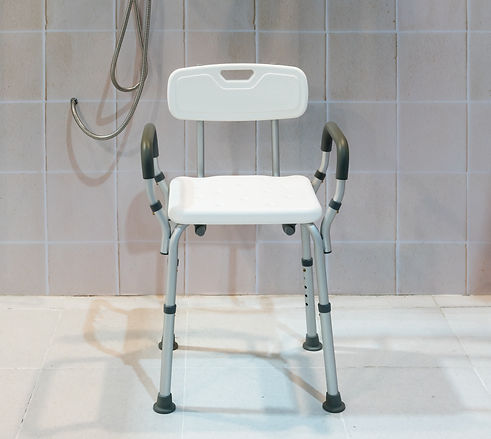 Padded shower chair with arms and back in bathroom with bright tile wall and floor..jpeg