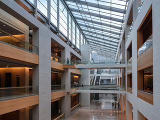 Çok katlı modern atriumda balkonlar, açık bağlantılar ve yüksek çatı geometrisi