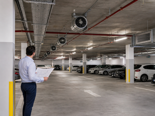 Kapalı otopark tavanındaki jet fanlar ve hava akımı planını inceleyen mühendis