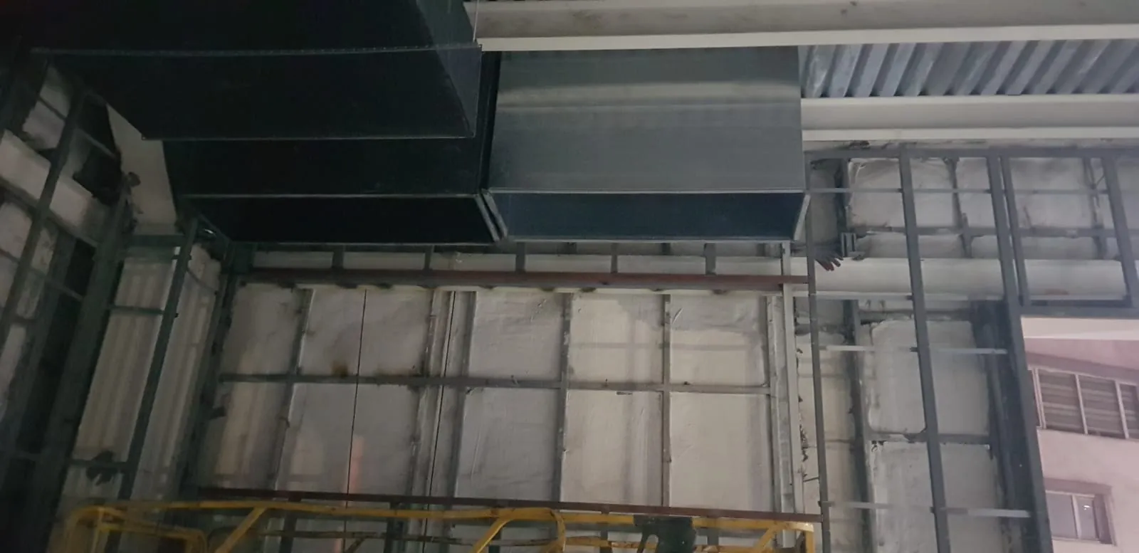 Tavan altında yan yana görünen açık dikdörtgen galvaniz kanal ağızları ve duvar karkası