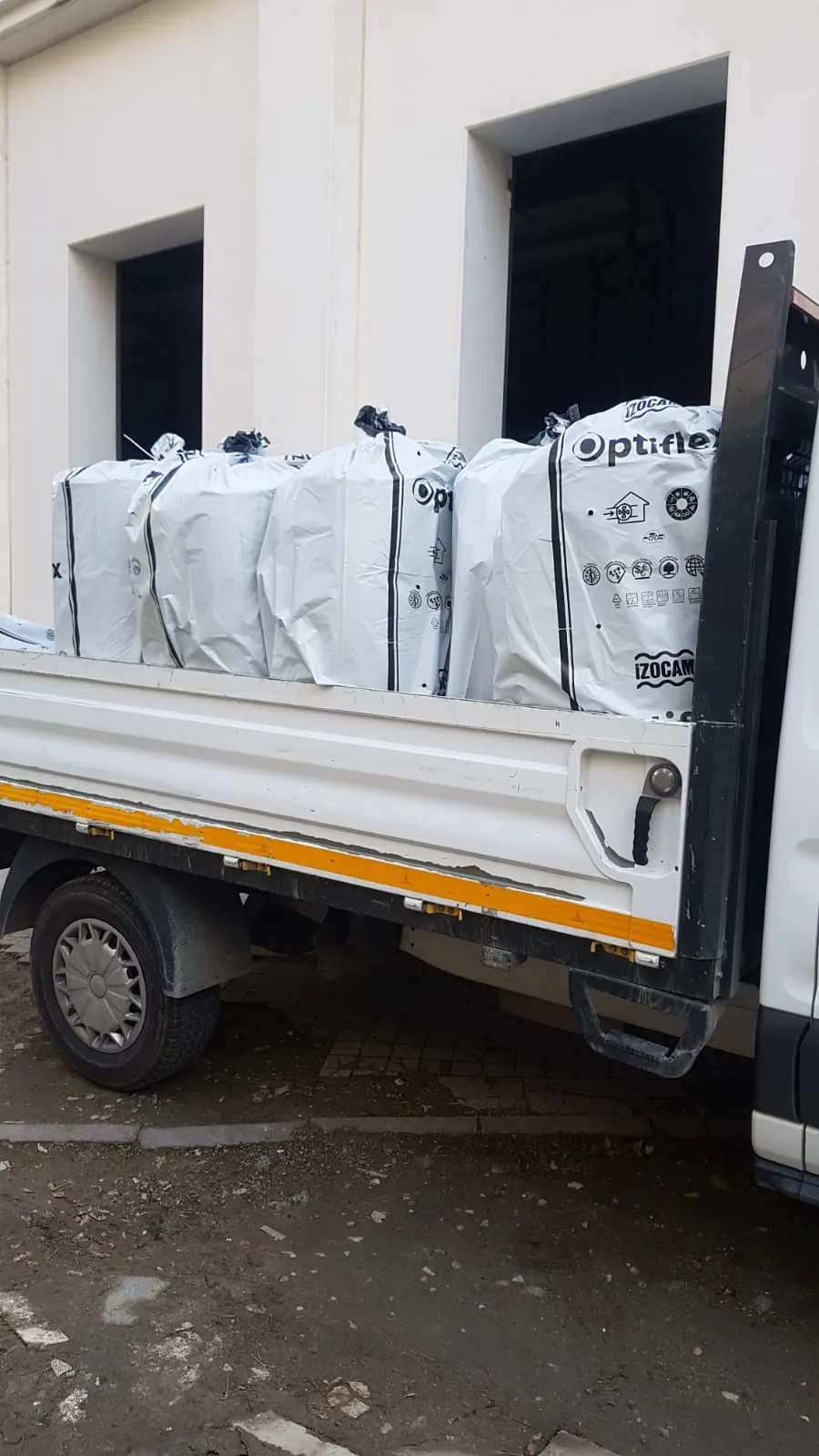 Bina önündeki kamyonetin kasasında beyaz ambalajlı İzocam yalıtım malzemeleri