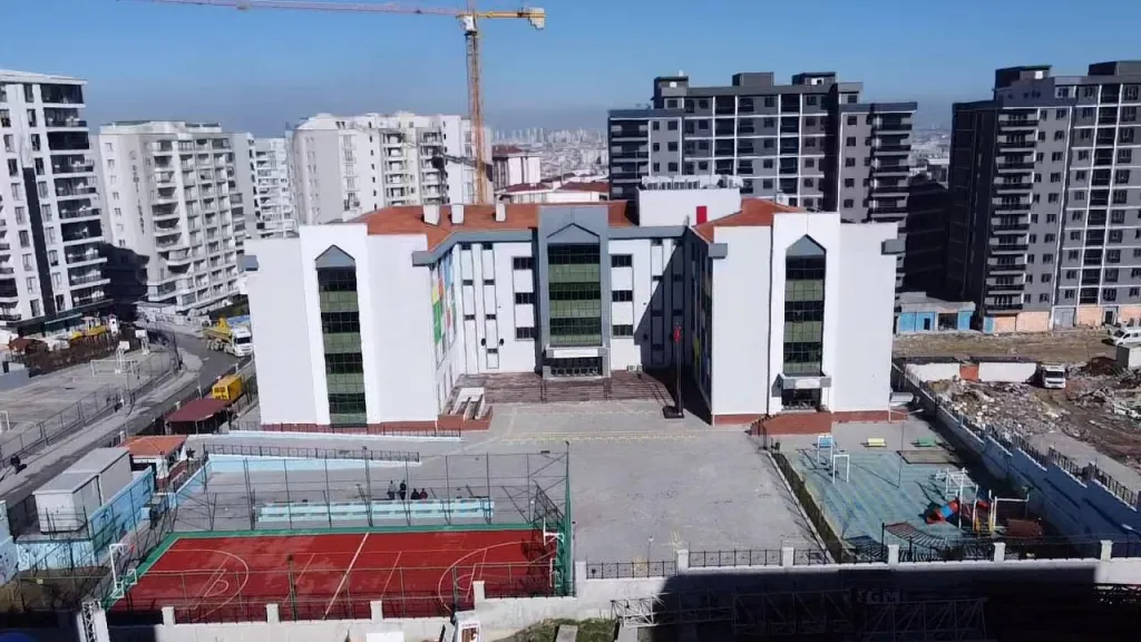 Esenyurt Barbaros Hayrettin Paşa İlkokulunun avlusu, basketbol sahası ve yeşil camlı giriş cephesi