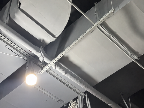 Close view of insulated ventilation duct bends and connections above the Mavi store