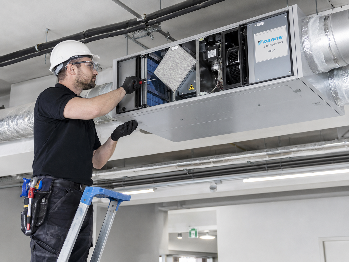Technician inspecting a ceiling-mounted ducted air-conditioning unit.