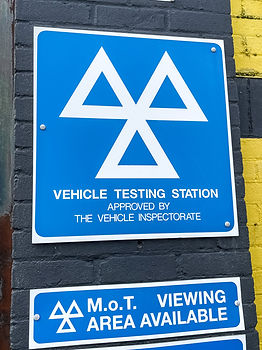 A UK MOT sign on a garage wall