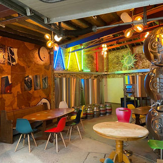 Inside a brewery with tables, seats, kegs and brewing equipment