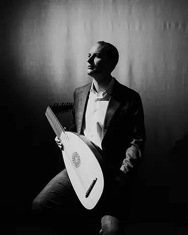 Dramatic, black and white photo of Toby Carr holding a lute and looking up