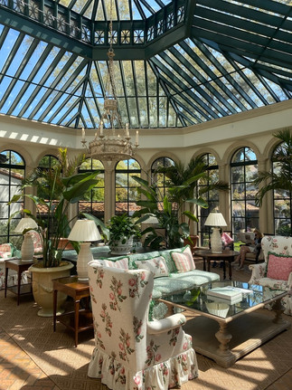 Elegant indoor conservatory at Sea Island Cloister featuring glass ceilings, floral seating, and Southern luxury resort design.