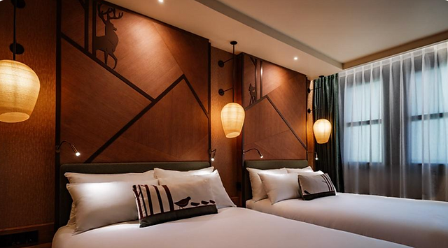 Guest room at Disney Sequoia Lodge featuring two beds, warm wood decor and subtle Bambi-inspired details.