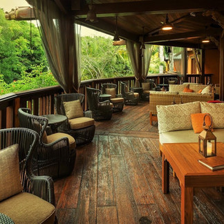 Open-air luxury resort lounge surrounded by tropical rainforest, showcasing relaxing eco-luxury travel accommodations.