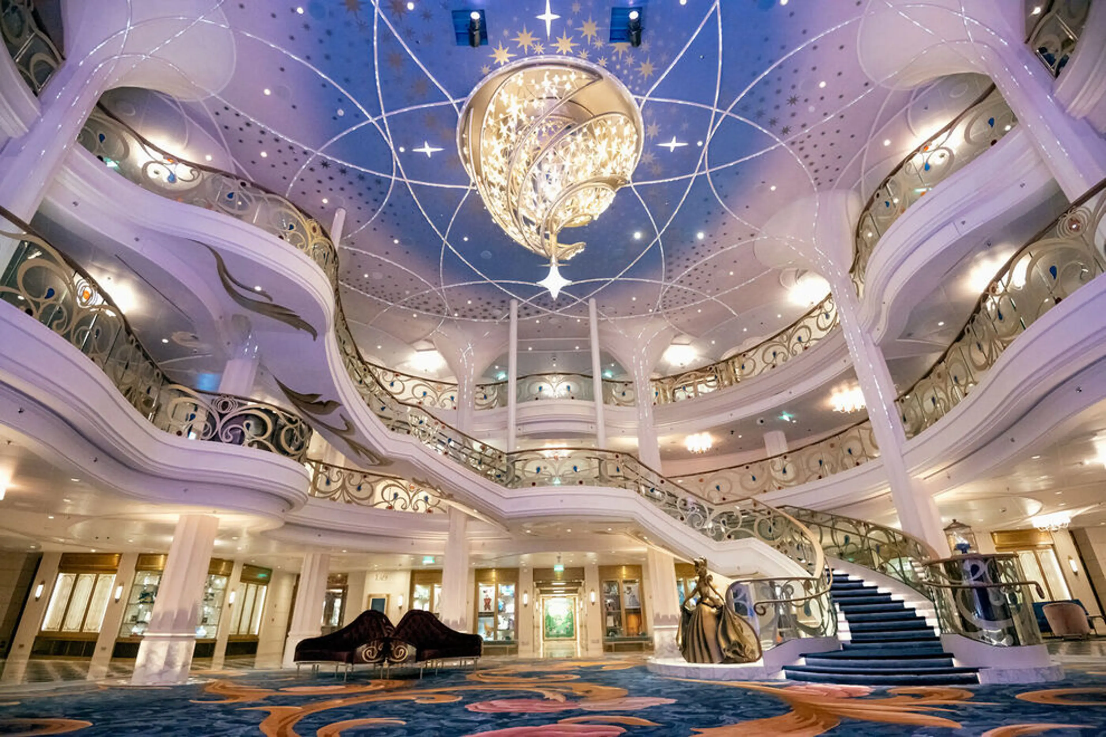 Grand atrium lobby onboard a Disney Cruise Line ship, featured in a Disney cruise vs Disney parks guide by Dani Garcia of Paradise and Pixie Dust Travel Agency.