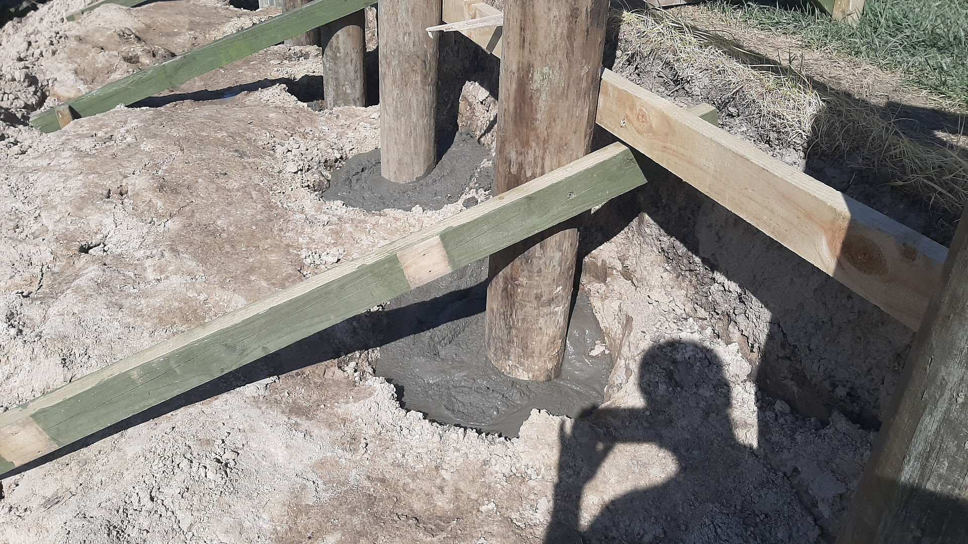 Close-up of concrete base stabilising timber posts for retaining wall construction in Napier