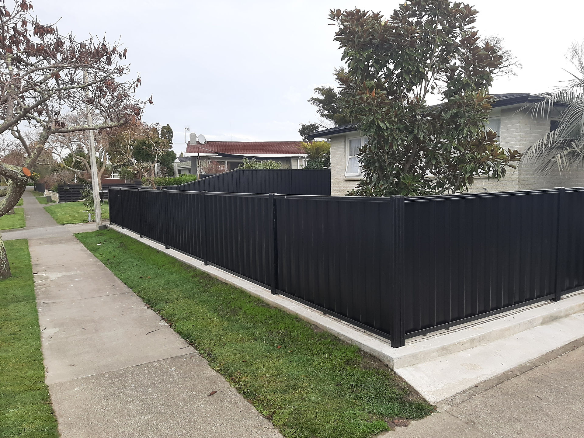 Corner section of colour steel fencing with clean concrete nib finish in Havelock North