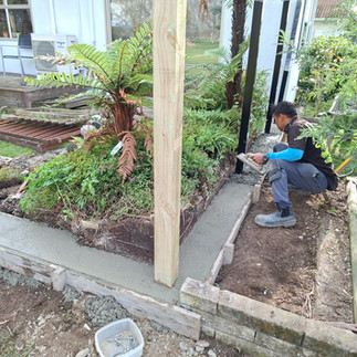 Builder installing timber fence framing on a reinforced concrete nib for a new boundary fence in Nap